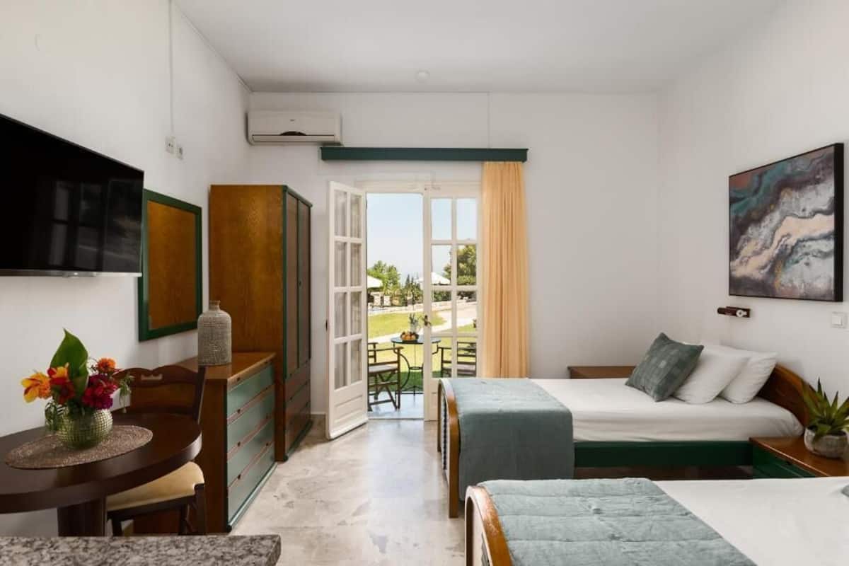 Una habitación con cama, escritorio, silla, televisor y ventana con vistas al exterior.