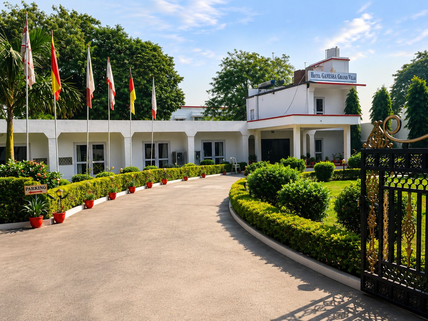 Ein Hotel mit Eingangsbereich, einer gebogenen Auffahrt, einem Tor und mehreren Flaggen.
