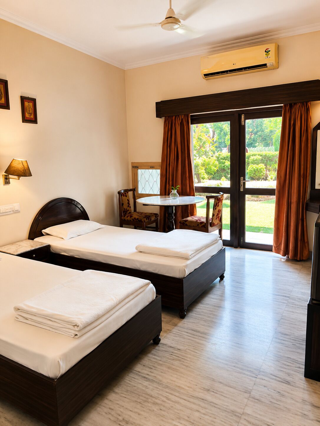 Une chambre d’hôtel avec deux lits, une petite table, une chaise, un appareil de climatisation et une vue sur l’extérieur.