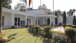 A building with a white exterior, a covered patio area, and a well-maintained garden with various plants and flowers.
