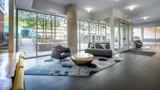 A modern lobby with a large glass wall, a central column, and seating areas.