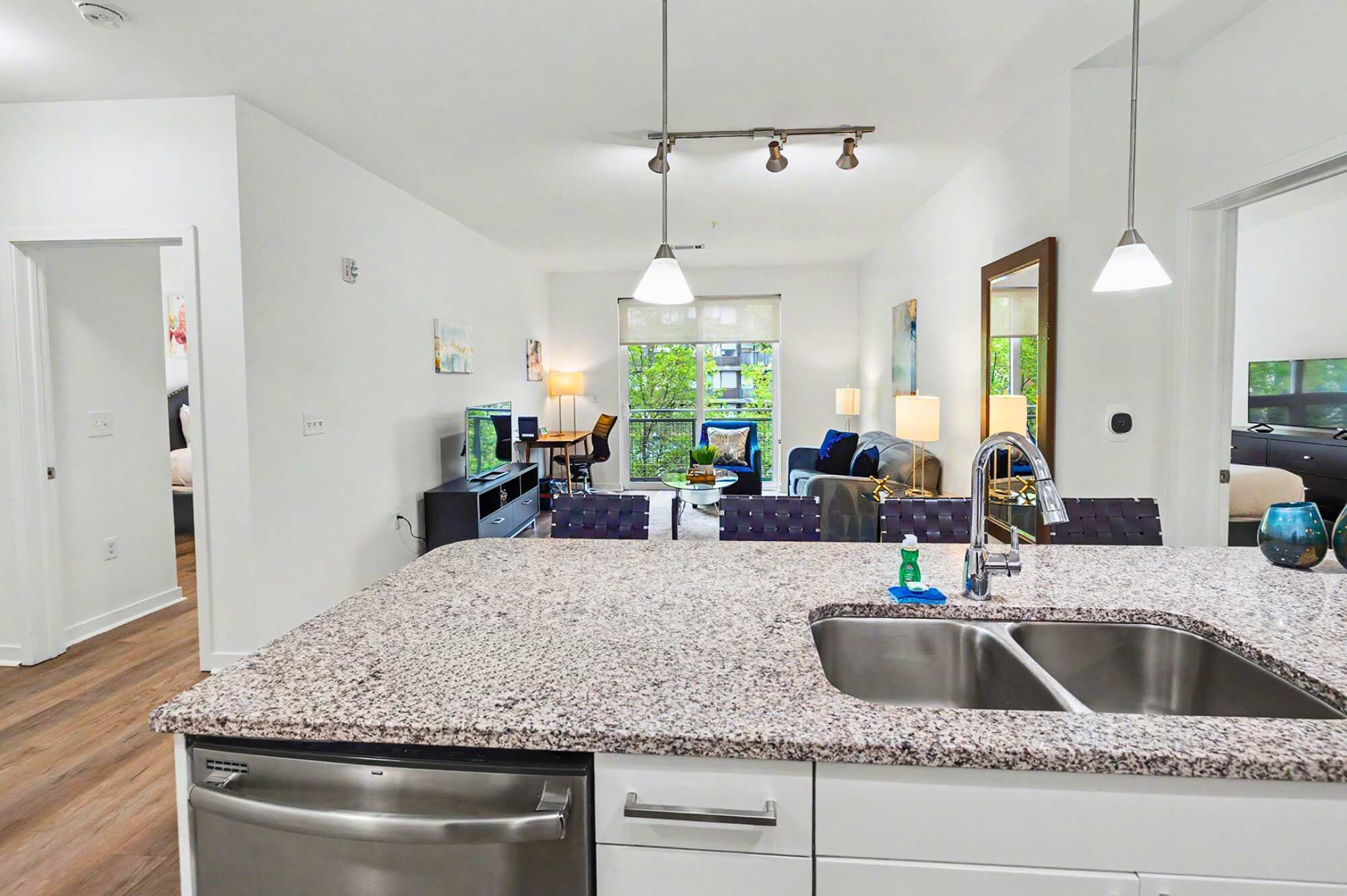 A modern kitchen with granite countertops, a stainless steel sink, and a dishwasher.