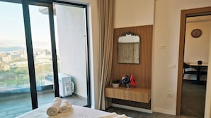 A hotel room with a bed, a bathroom vanity, a mirror, and a view of the city. - Sunny Stay apartment in Ksamil (Ksamil)