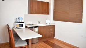 A compact kitchen with a microwave, sink, and wooden cabinets. - Diva Serviced Apartments (Jeddah)