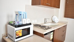 A compact kitchenette with a microwave, sink, and cabinet. - Diva Serviced Apartments (Jeddah)