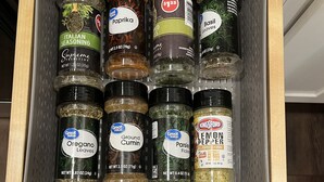Un mueble espeziero con diversas especias, incluyendo hierbas italianas, pimentón, albahaca, orégano, comino molido, perejil, pimienta de limón y ajo en polvo.