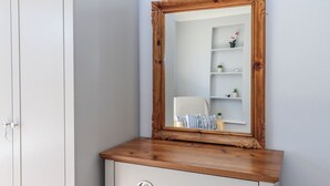 A white wardrobe with a wooden top and a mirror with an ornate frame. - The Arches (Torquay)