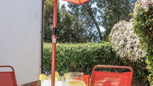 An outdoor dining area with a table, chairs, a glass pitcher, and a bowl of croissants. - The Arches (Torquay)