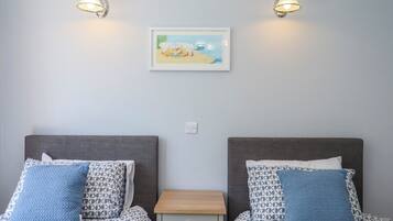 Una habitación doble con dos camas, una mesita de noche pequeña y dos lámparas de pared.