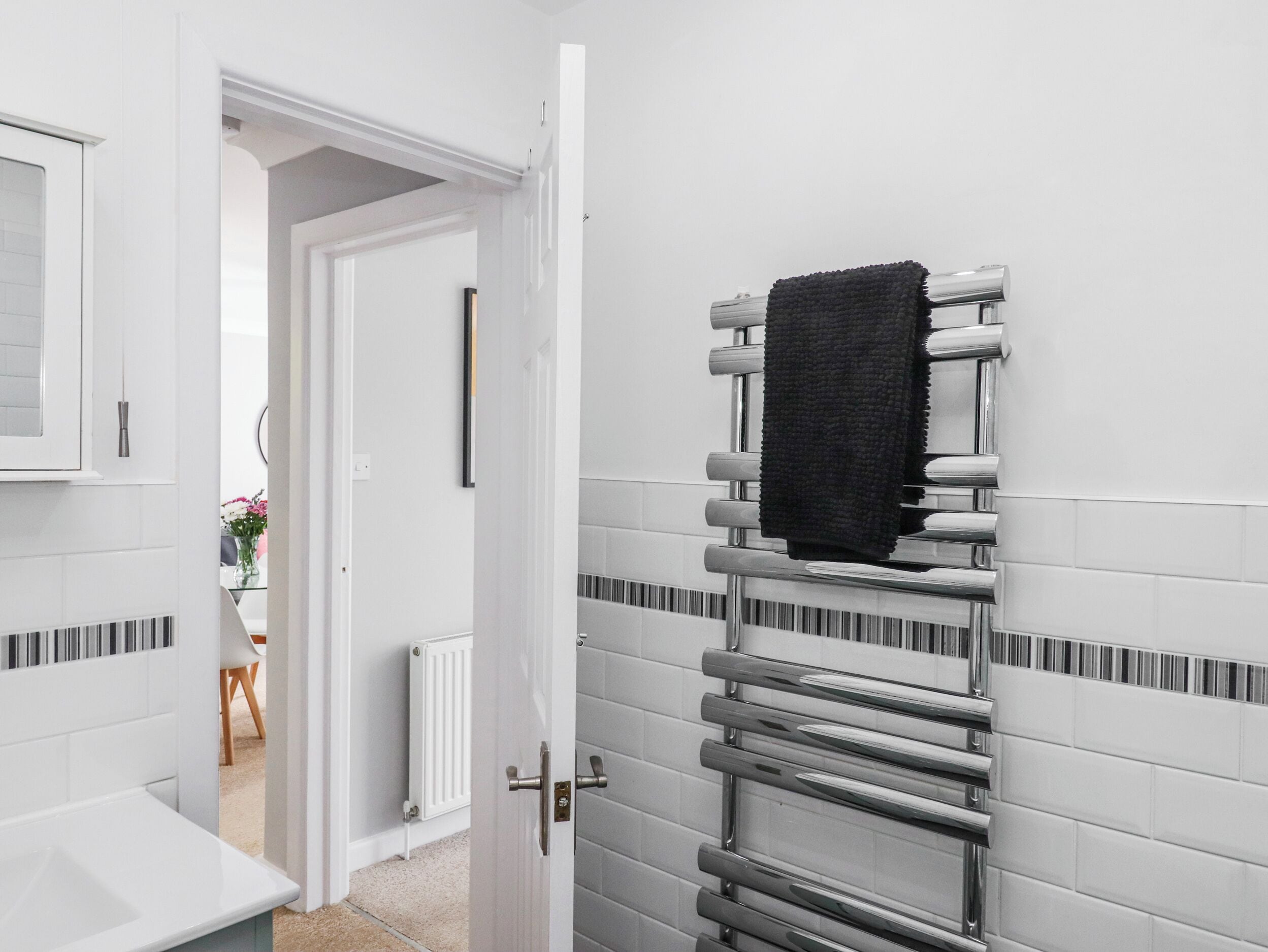 Une salle de bain avec une porte blanche, un porte-serviettes avec une serviette, et un radiateur blanc.