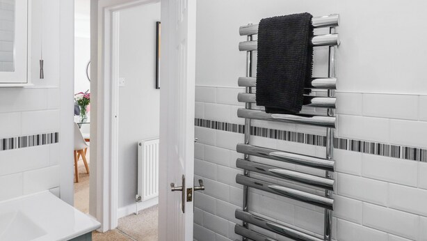 Une salle de bain avec une porte blanche, un porte-serviettes avec une serviette, et un radiateur blanc.