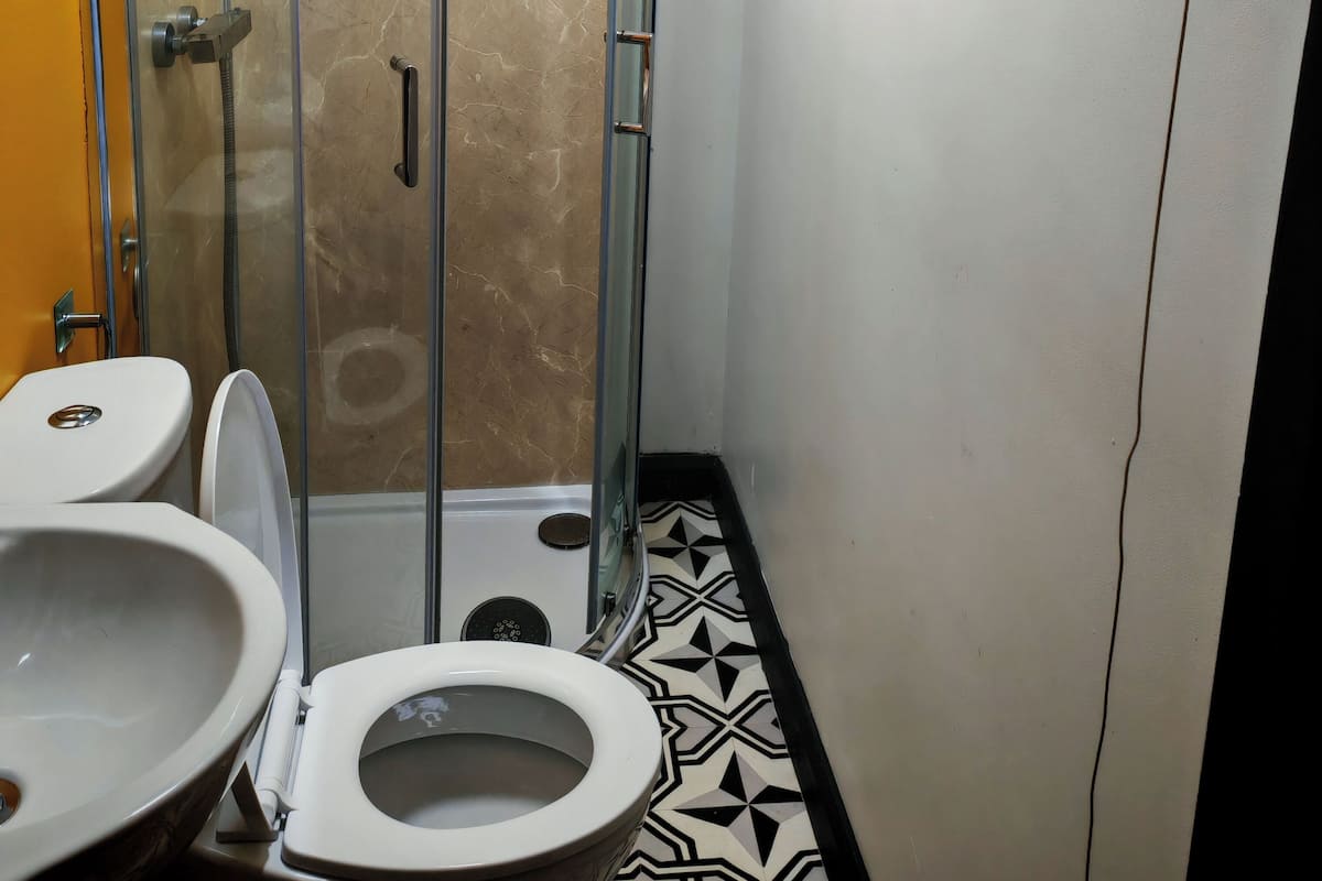 A bathroom with a glass-enclosed shower, a toilet, and a sink.