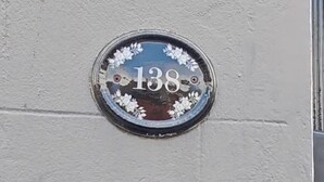 A house number plaque and a Phoenix B&B sign with a bird and castle image.