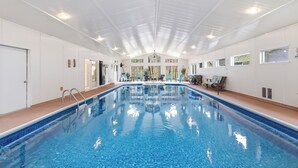 An indoor swimming pool with clear blue water, white walls, and a ceiling with skylights.