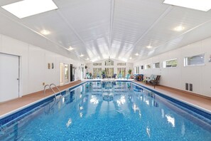 Ein Innenpool mit klarem, blauem Wasser, weißen Wänden und einer Decke mit Oberlichtern.