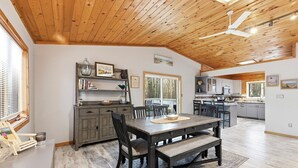 A spacious dining area with a wooden ceiling, a large window, and a view of the outdoors.