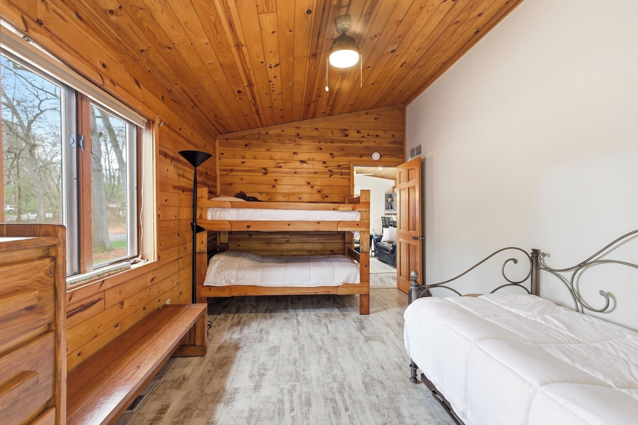 Ein Holzblockhaus-Innenraum mit Etagenbetten, einer Bank und einem Einzelbett.