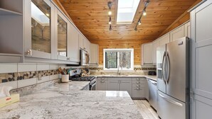 A kitchen with granite countertops, stainless steel appliances, and a wooden ceiling.