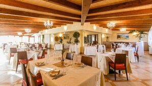 Un restaurante con varias mesas, vigas de madera en el techo y candelabros.