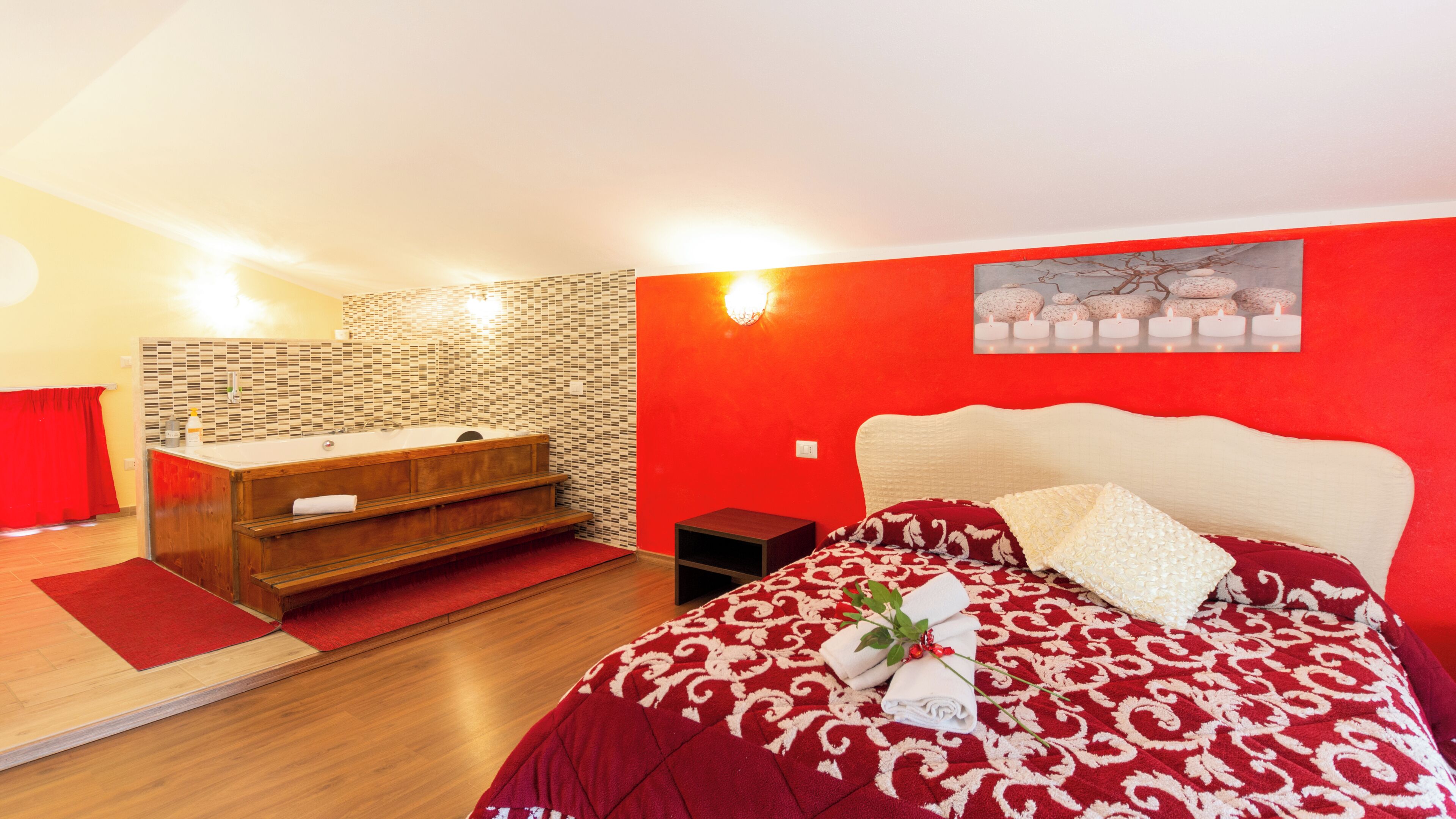 Ein Schlafzimmer mit einem Bett, einer Holzkommode, einer roten Wand und einer Wandleuchte.