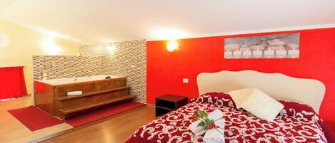 Ein Schlafzimmer mit einem Bett, einer Holzkommode, einer roten Wand und einer Wandleuchte.