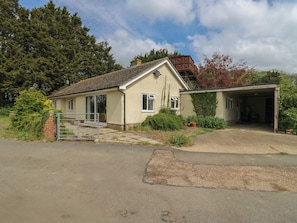 A single-story house with a garage, a front gate, and a driveway leading to the entrance. - The Lodge (Colchester)