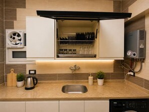 Eine moderne Küche mit integriertem Geschirrspüler, einer Spüle und einer Arbeitsplatte mit Wasserkocher und Schneidebrett.