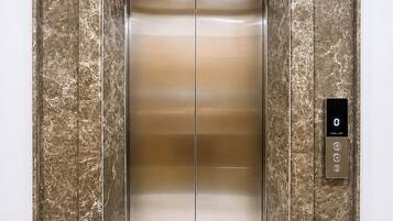 An elevator with a marble wall and a digital control panel.
