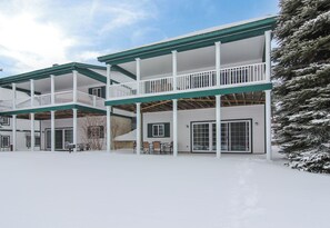 Een meerlaags gebouw met een overdekte patio, grote ramen en een met sneeuw bedekte grond.