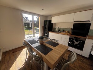 A modern kitchen with a dining area, wooden flooring, and a view of the outdoors. - Seaside house, in residence with swimming pool, tennis, pétanque, beach access on foot (Batz-sur-Mer)