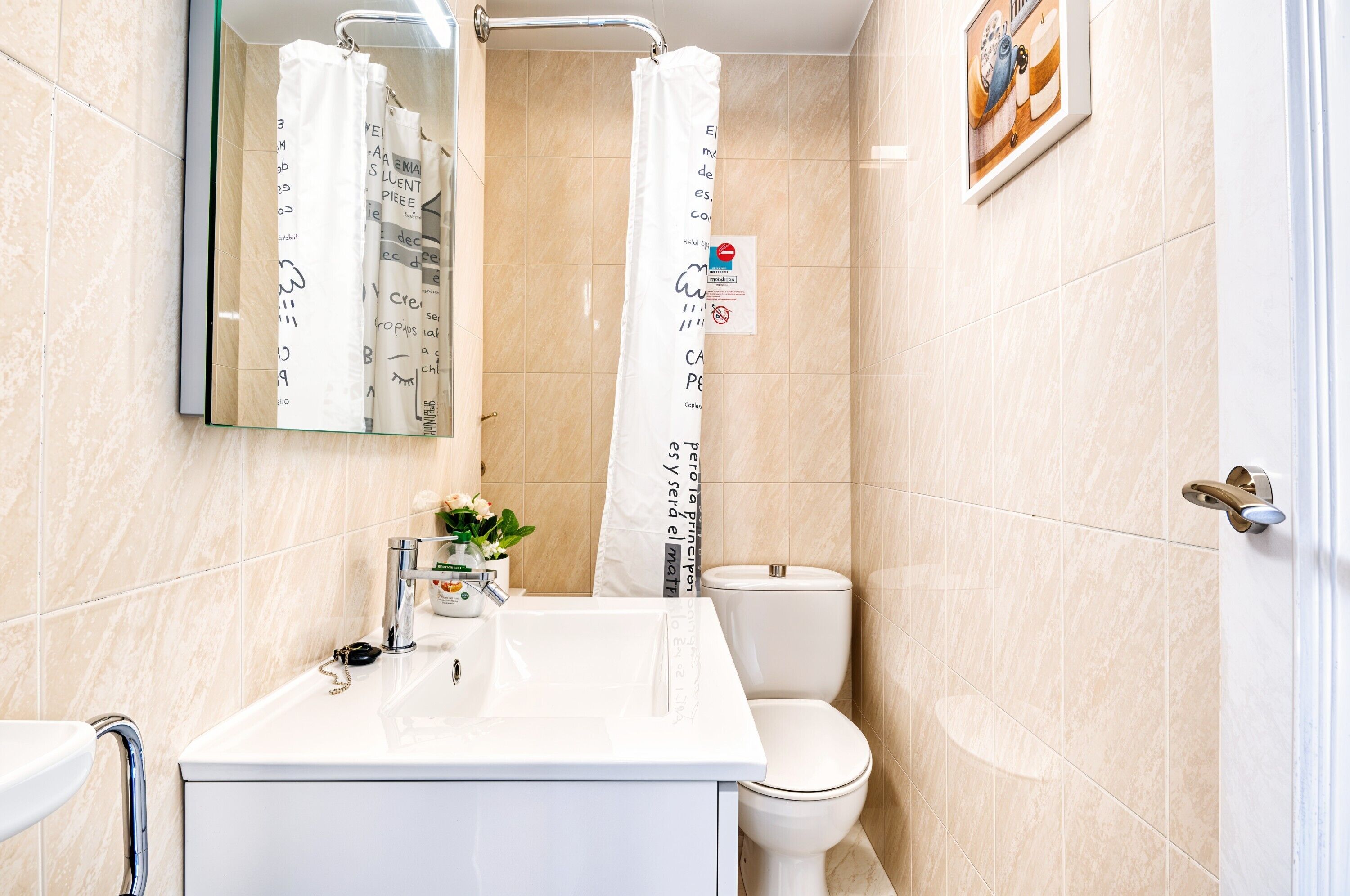 A bathroom with a white sink, a toilet, and a shower curtain with text.