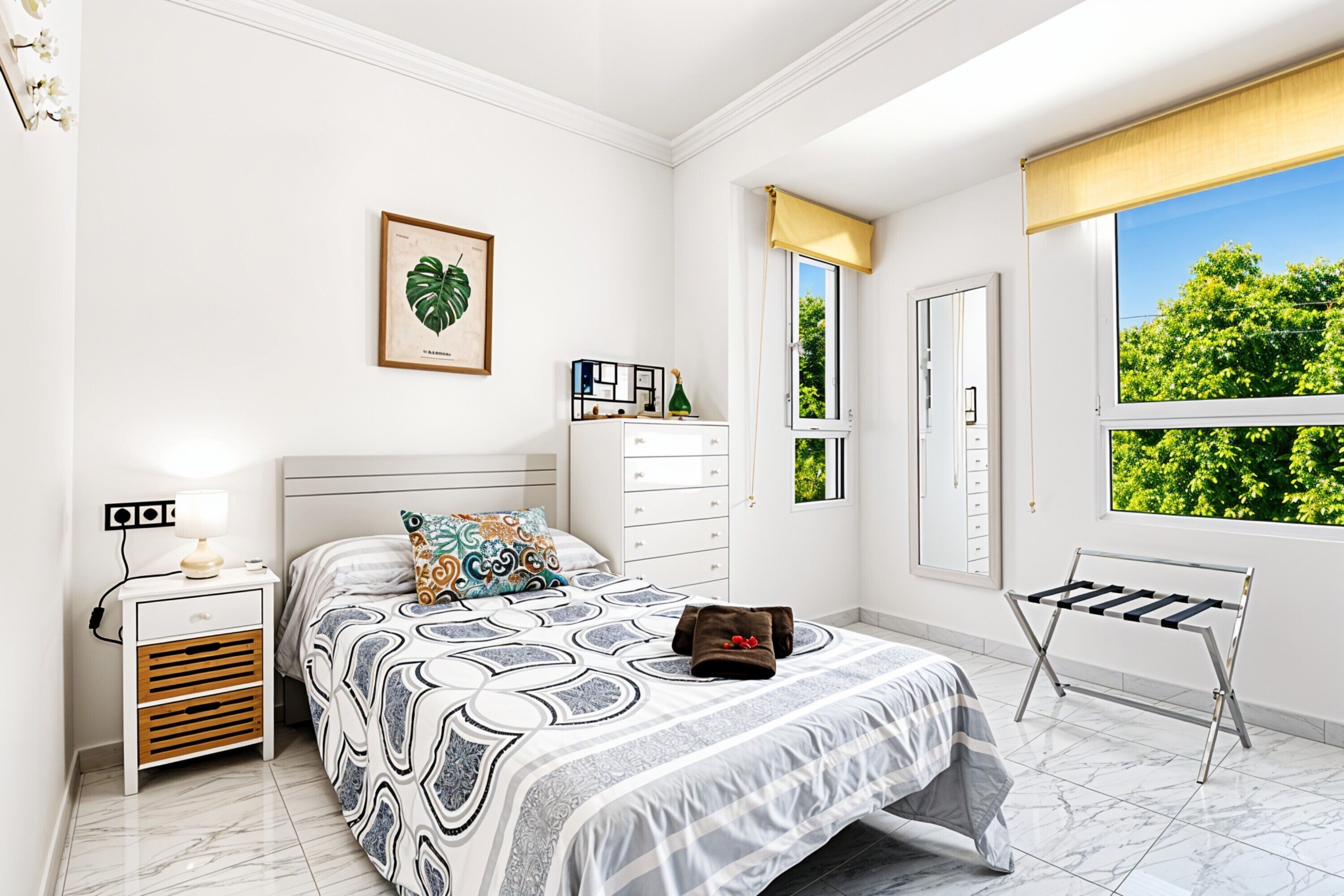 A bedroom with a bed, a nightstand, a dresser, a window with a view, and a radiator.
