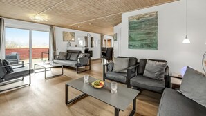 Een ruime woonkamer met een hoge plafond, moderne meubels en grote ramen.