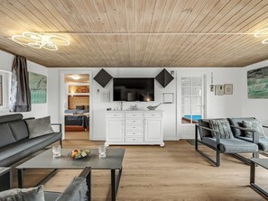 A modern living room with a wooden ceiling, a flat-screen TV, white cabinetry, and a dining area. - "Wenke" - 300m to the fjord by Interhome (Hvide Sande)
