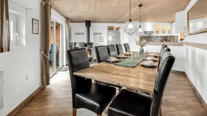 Een eethoek met een houten tafel, zwarte stoelen en hanglampen.