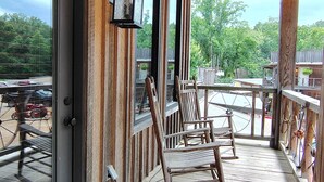 A wooden porch with a glass door, a rocking chair, and a table. - Prospector Pickwick Lake / Presidential Suite (Hardin County)