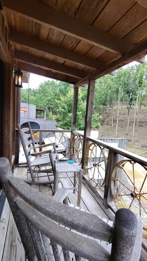 Een houten veranda met schommelstoelen en een groot rad.