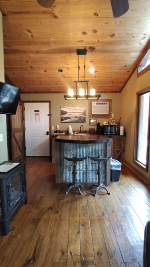 Une cuisine rustique avec un plancher en bois, un coin bar et un ventilateur de plafond.