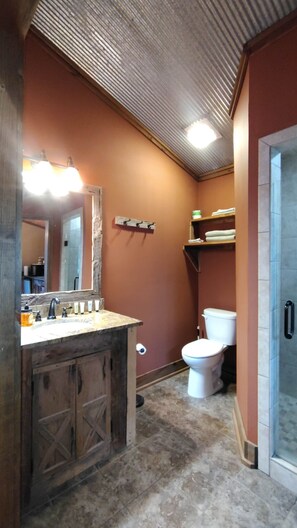 Une salle de bain avec un meuble-lavabo en bois, des toilettes, une étagère avec des serviettes et un miroir.