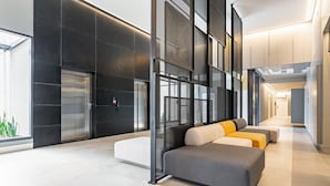 A modern lobby with a seating area, elevators, and a glass wall. - Modern Studio | Pool | Gym #SG10 (Florianópolis)