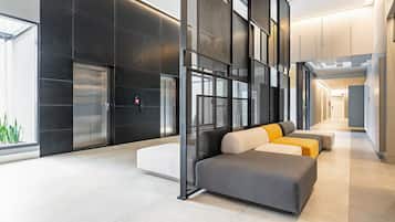 Un vestíbulo moderno con área de descanso, ascensores y una pared de vidrio.