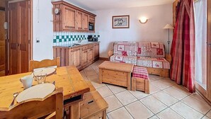 Cuina compacta amb armaris de fusta, un frontissó de rajoles i una zona de menjador amb taula i cadires de fusta.