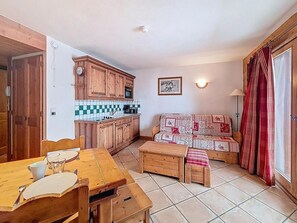 Eine kleine Küche mit Holzausbau, einer gefliesten Spritzschutzwand und einem Essbereich mit Holztisch und Stühlen.