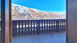 Un balcón con baranda de metal y vistas a montañas nevadas bajo un cielo azul despejado.