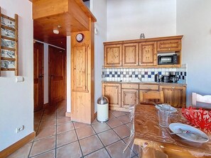 A kitchen with wooden cabinets, a microwave, and a tiled backsplash. - 2nd floor, swimming pool, balcony, tv, ski locker, 35m², Les Menuires (Les Menuires)