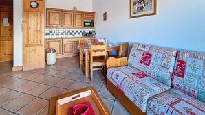 Una sala de estar con sofá, mesa de comedor y armarios de madera.