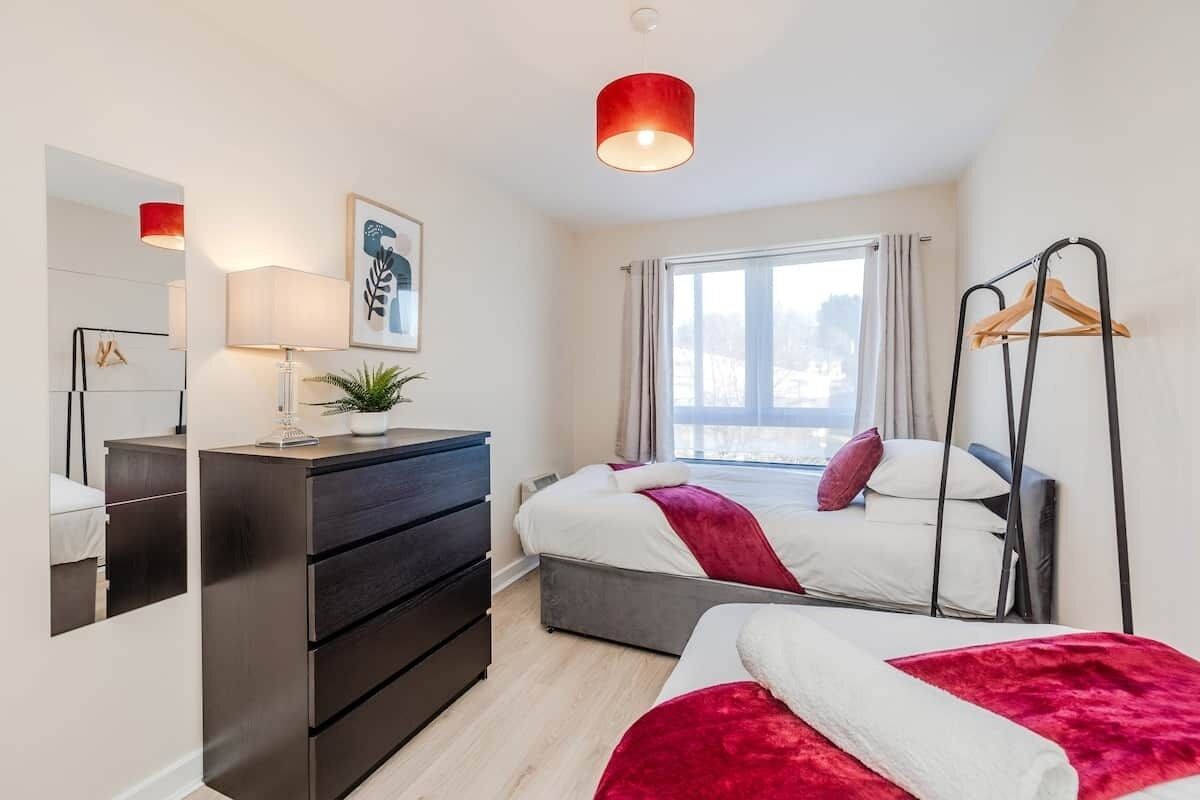 Un dormitorio moderno con cama, cómoda y lámpara colgante.