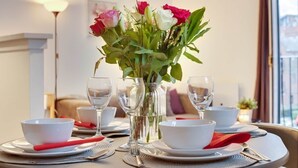 A dining table set with white bowls, red napkins, and clear glassware, with a vase of flowers in the center. - Spacious 3 Bed City Centre Apartment, Free Parking, sleeps 5 (Newcastle upon Tyne)