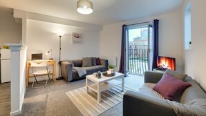 A modern living room with a sofa, a coffee table, a desk, and a fireplace. - Spacious 3 Bed City Centre Apartment, Free Parking, sleeps 5 (Newcastle upon Tyne)
