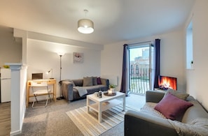 Una sala moderna con sofá, mesa de centro, escritorio y chimenea.